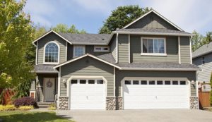 Gray and muted green house with two white garage doors